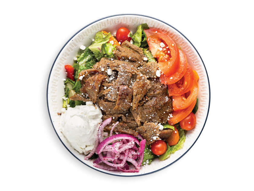 Beef and lamb gyro salad bowl with romaine, vegetables, herbs and pita